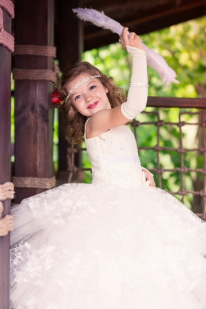 Charming little girl in a beautiful dress in a park outdoorの写真素材