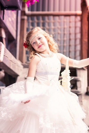 Charming little girl in a beautiful dress in a park outdoorの写真素材