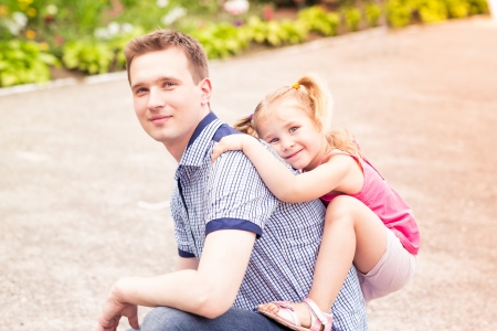 Happy smiling young father and daughter playing in the parkの写真素材