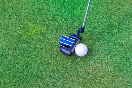 Golf stick and ball near the hole on the grass background.