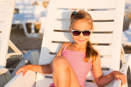 Adorable kid in sunglasses sunbathing on a lounge on a beachの写真素材