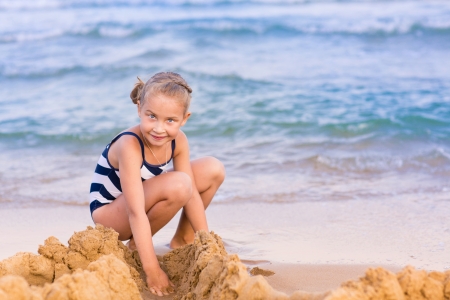 Adorable little girl building a sandcastlle at the seashoreの写真素材