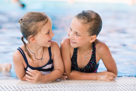 Two cute little girls in swimming pool posingの写真素材