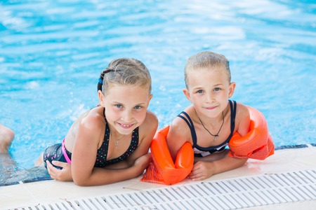 Two cute little girls in swimming pool posingの写真素材