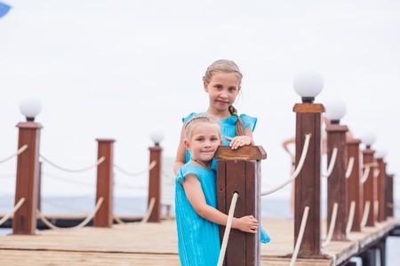 Portrait of beautiful little girls, sisters on the pier at the seasideの写真素材
