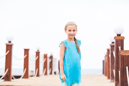 Portrait of beautiful little girl posing on the pier at the seasideの写真素材