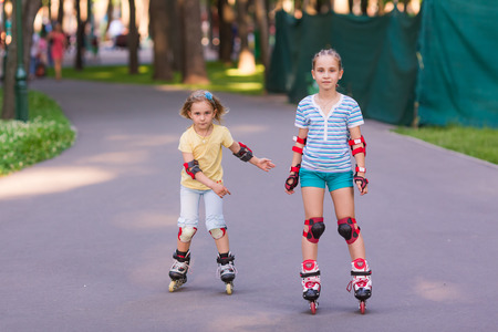 Two little girls rollerskating in the park outdoorの写真素材