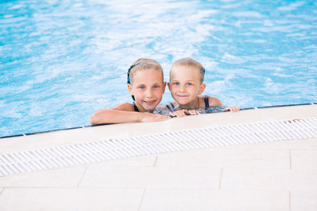Two cute little girls in swimming pool posing