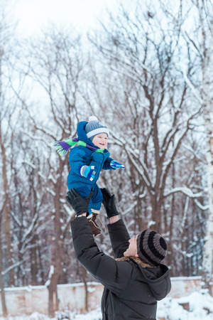 Happy father and baby playing on snow in winter parkの写真素材