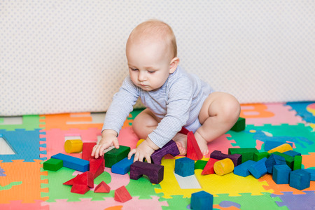 Cute little baby playing with colorful toys at homeの写真素材
