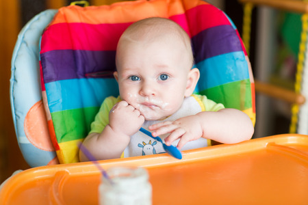 Adorable baby eating in high chairの写真素材