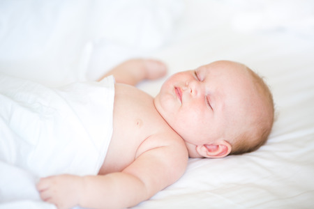 Peaceful newborn baby sleeping on a bedの写真素材