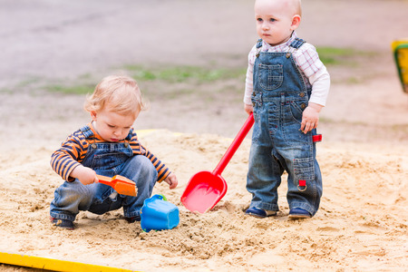 Two baby boys playing with sand in a sandboxの写真素材