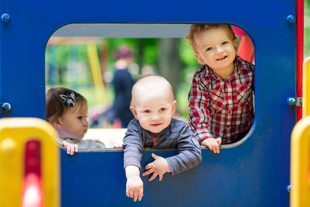 Three babies in the toy car on the playgroundの写真素材