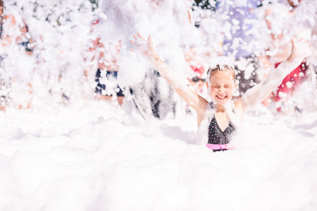 Foam Party on the beach. Cute little girl having fun and dancing.の写真素材