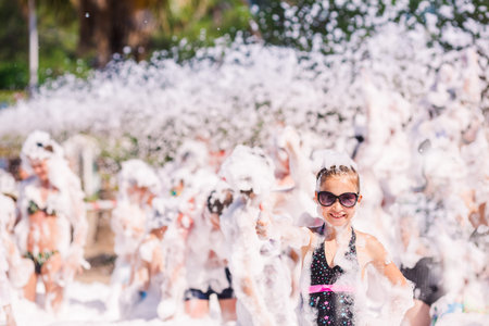 Foam Party on the beach. Cute little girl having fun and dancing.の写真素材