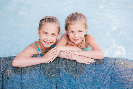 Two cute little girls in swimming pool posing