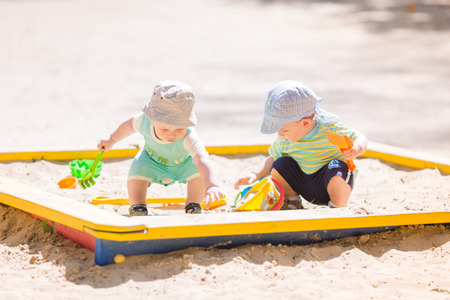 Two baby boys playing with sand in a sandboxの写真素材