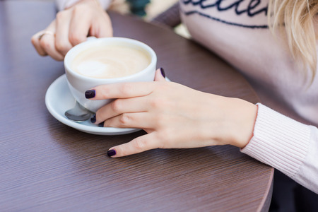Hands of beautiful young girl holding coffe cup, coffee break conceptの写真素材