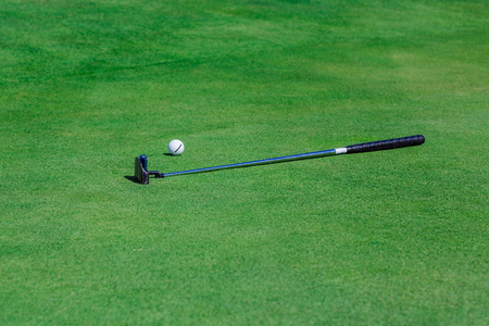 Golf stick and ball near the hole on the grass background.の写真素材