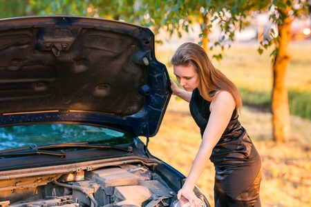 Beautiful business woman near her broken car, tring to repairの写真素材