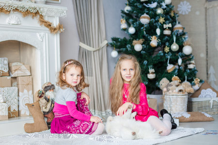 Happy kids near Xmas tree with presents near fireplaceの写真素材