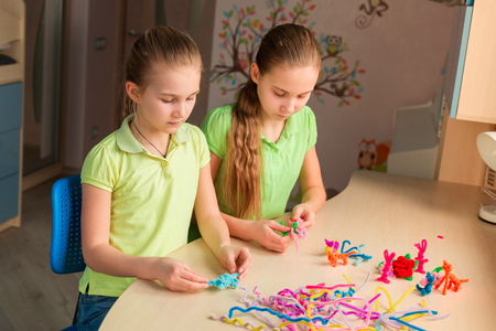 Cute little girls creating toys with chenille sticks at the table. Creativity and handmade concept.の写真素材