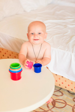 Cute little baby boy playing with stacking cups in the roomの写真素材