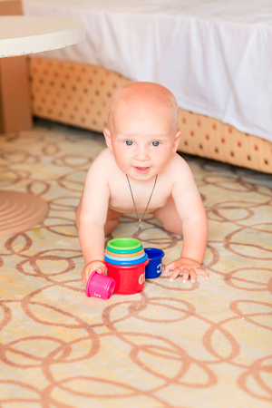 Cute little baby boy playing with stacking cups in the roomの写真素材