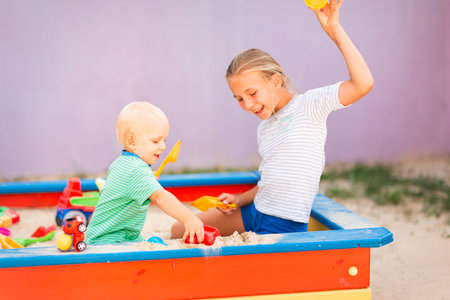 Cute baby boy playing with his sister with toys in the sandbox outdoorの写真素材