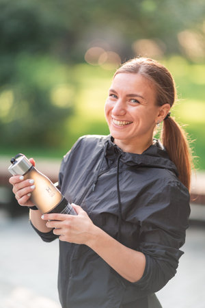 Happy sportive woman drinking water during fitness exercises, jogging