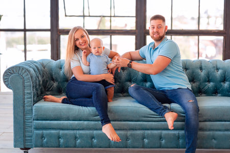 Young happy family with the baby at home indoors
