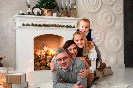 Happy family having fun together at Christmas eve near fireplace