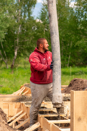 Construction worker laying cement or concrete into the foundation formwork with automatic pump....