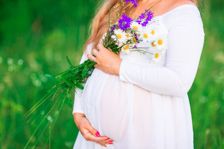 Beautiful young pregnant woman relaxing in nature on a beautiful sunny day. Close up of pregnant...