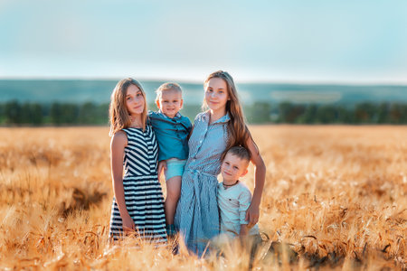 Happy kids having fun in golden wheat field at the sunset