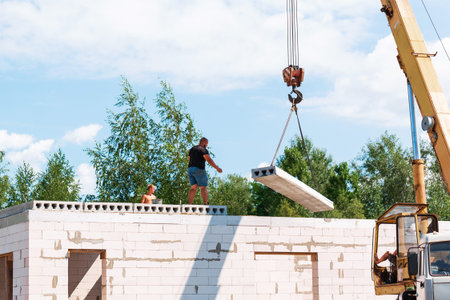 Builder worker installing concrete floor slab panel at building construction site. Second floor...