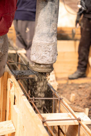 Close up of construction worker laying cement or concrete into the foundation formwork with automatic pump. Building house foundationの写真素材