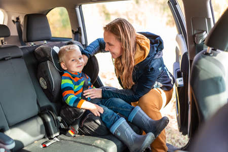 Mother fastening safety belt for her baby boy in his car seat. Children's Car Seat Safetyの写真素材