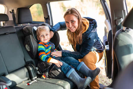 Mother fastening safety belt for her baby boy in his car seat. Children's Car Seat Safetyの写真素材