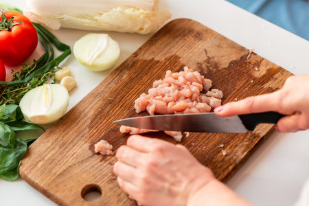 Cooking chicken tenders at home. Slicing chicken fillet into small pieces for the mince on the...