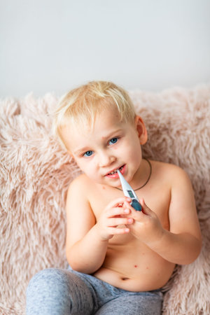 Little baby boy with Varicella virus or Chickenpox bubble rash checking his temperature at home