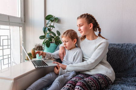 Cute kids having video call with grandparents on laptop during quarantine lockdown. Stay at home, distance communication conceptの写真素材