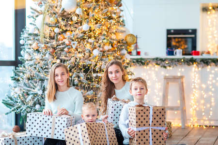 Happy kids sibilings near the Christmas tree with the present boxes. Christmas morning, christmas mood conceptの写真素材