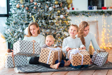 Happy kids sibilings near the Christmas tree with the present boxes. Christmas morning, christmas mood conceptの写真素材