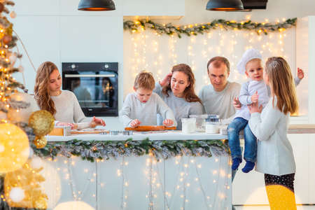 Big happy family making gingerbread, cutting cookies of gingerbread dough, having fun. Festive food, cooking process, family culinary, Christmas and New Year traditions concept. Christmas bakery.の写真素材