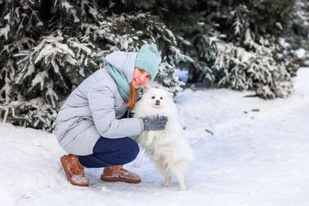 Happy teenage girl having fun playing with her dog on the snow in winter. Snow games. Winter vacation.の写真素材