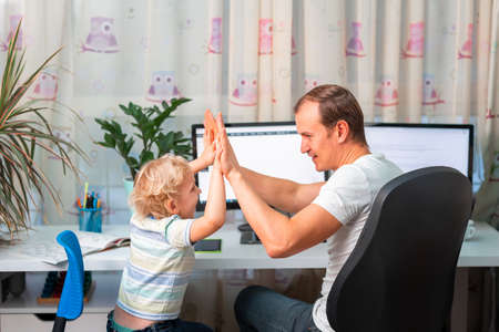 Father with kid trying to work from home during quarantine. Stay at home, work from home concept during virus pandemicの写真素材