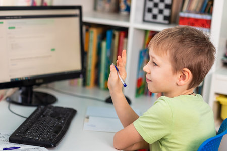 Little young school boy working at home with a laptop and class notes studying in a virtual class....