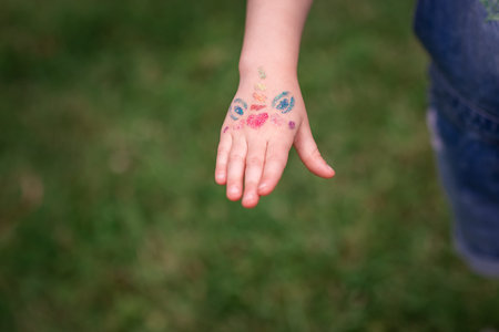 Shimmering sparkling glitter tattoo on a child's hand at a birthday party. Body art